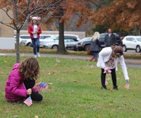 students placing american flags in lawn