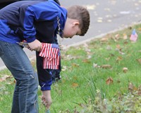 student placing small american flag in ground