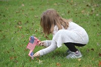 student placing small american flag in grass