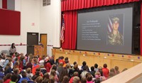 student speaking in front of peers at veterans day assembly