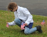student placing american flag in ground