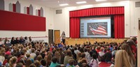 wide shot of teacher speaking at veterans day assembly