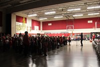 wide shot of students singing in gymnasium