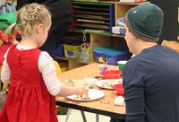 adult and student decorating gingerbread house