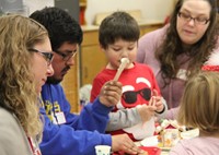 students and adults decorating gingerbread creations