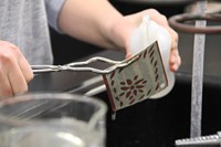 close up of student pouring liquid onto ornament