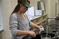 student pouring liquid on ornament in sink