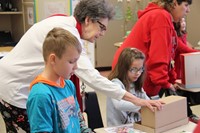 teacher helping student with habitat shoe boxes