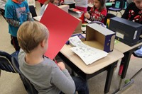 student cutting red paper