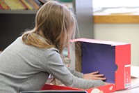 student placing blue paper into shoebox