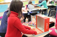 student placing paper in bottom of shoebox