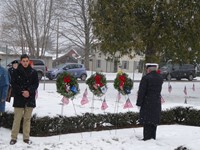 man standing facing wreaths