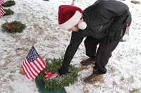 close up of student placing wreath on grave