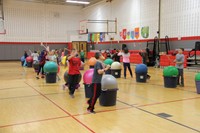 students walking around exercise balls holding drum sticks