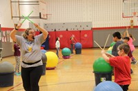 instructor and student holding drum sticks up in the air