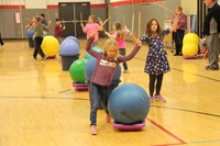 students walking around large balls holding up drum sticks