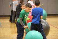 student hitting large ball with drum stick