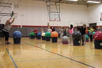 instructor and students hold drum sticks in the air