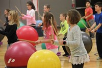 more students hitting drum sticks on large balls