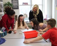 teacher watching students work on project