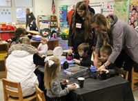 families working on making penguins out of milk cartons