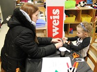 student and adult making penguin out of milk carton