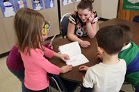 elementary students reading high school students book to her