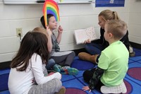 high school student reading her story to elementary students