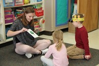 high school student reading story to two elementary students
