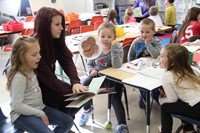 high school student reading to elementary students