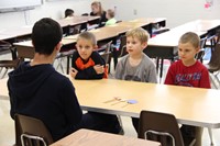 high school student talking to three elementary students