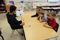 high school student reading to three elementary students