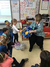 student brushing toy dragons teeth