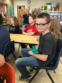 student waving wearing glove