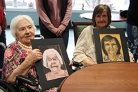 two women smiling holding drawings