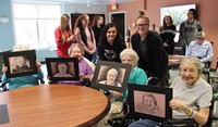 students and residents holding drawings