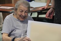 woman sitting and smiling looking at drawing