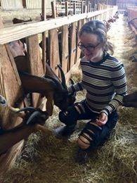 student sitting next to goats petting them