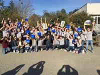 students holding up blue boxes