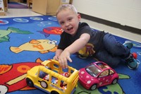 student playing with toy school bus