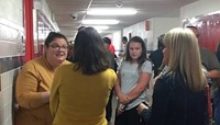 people talking to teacher in hallway