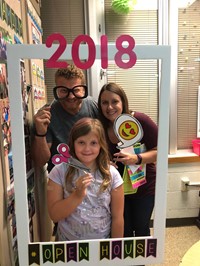 two adults and student with photo props at open house