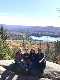 students sitting on rock on top of mountain