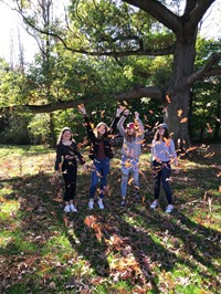 students throwing leaves in the air