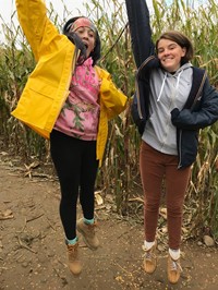 students jumping in corn maze