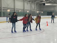 students holding hands ice skating