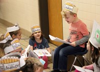 first grade student reading to peers