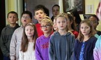 wide shot of chorus performing for residents