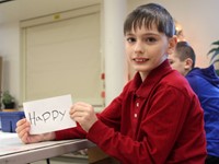 student holding up art project that says happy