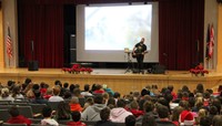 wide shot of jared campbell performing for students